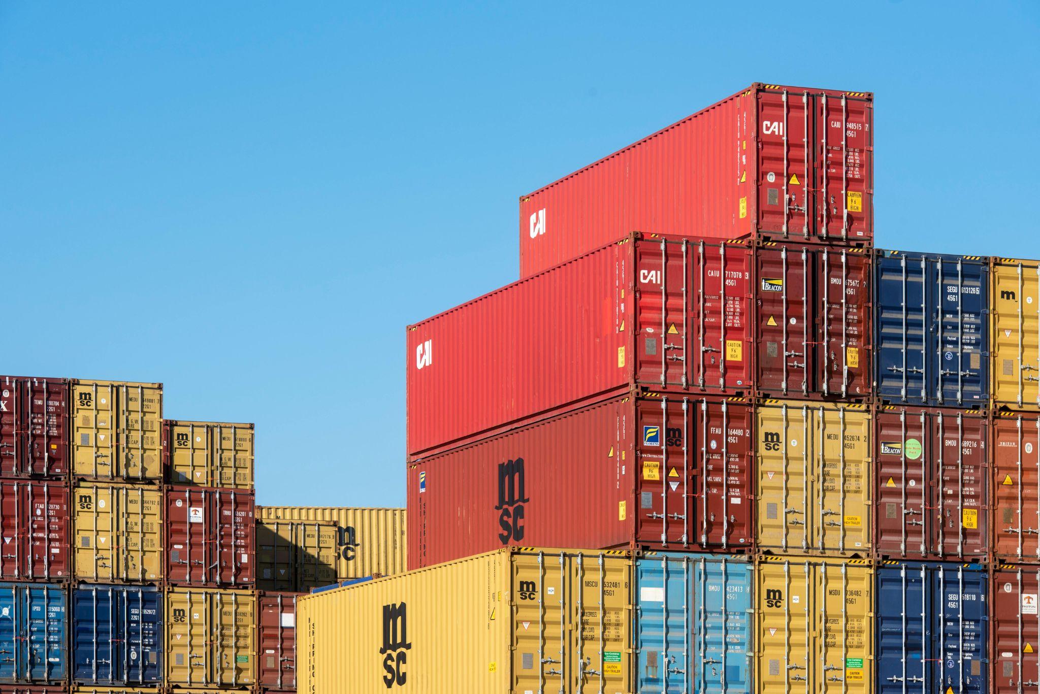 Stacked cargo shipping containers at an international port terminal, ready for export and import logistics operations